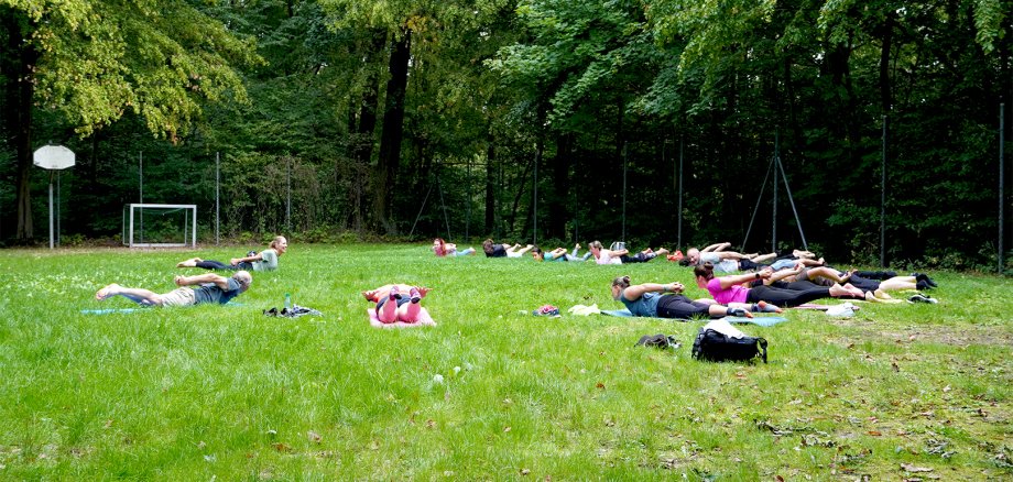 Beschäftigte der Stadt machen Yoga auf einer Rasenfläche