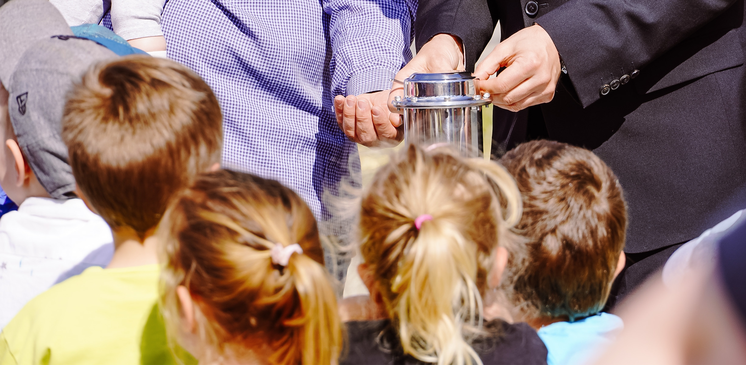 Kinder der Kita Pfiffikus gucken gespannt auf die befüllte Zeitkapsel.