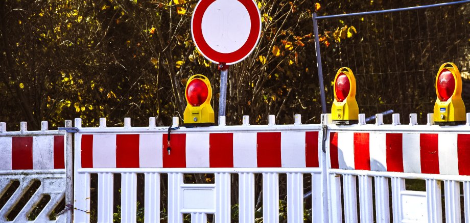 Warnbarken und entsprechende Baustellenschilder sperren eine Straße.