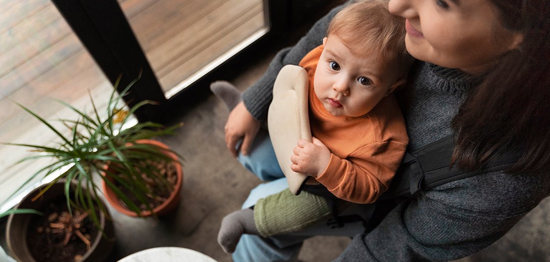 Kleinkind sitzt mit Kaffeetasse am Tisch.