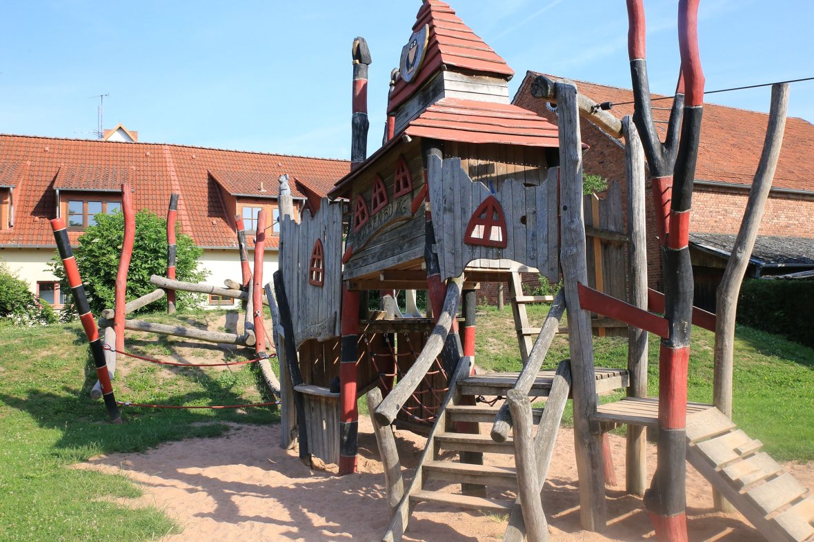 Ein Spielhaus aus Holz mit einer Brücke.