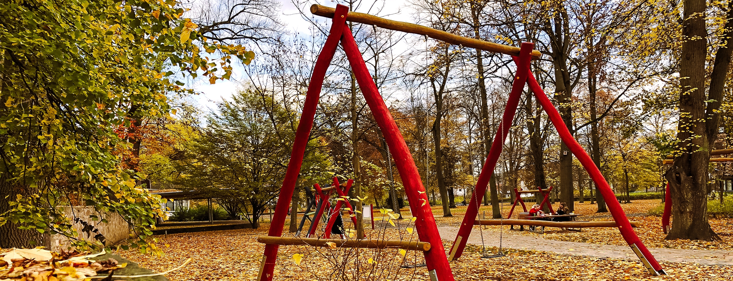 Die große Schaukel des Schaukelwaldes im Schlosspark steht inmitten herbstlicher Blätter.