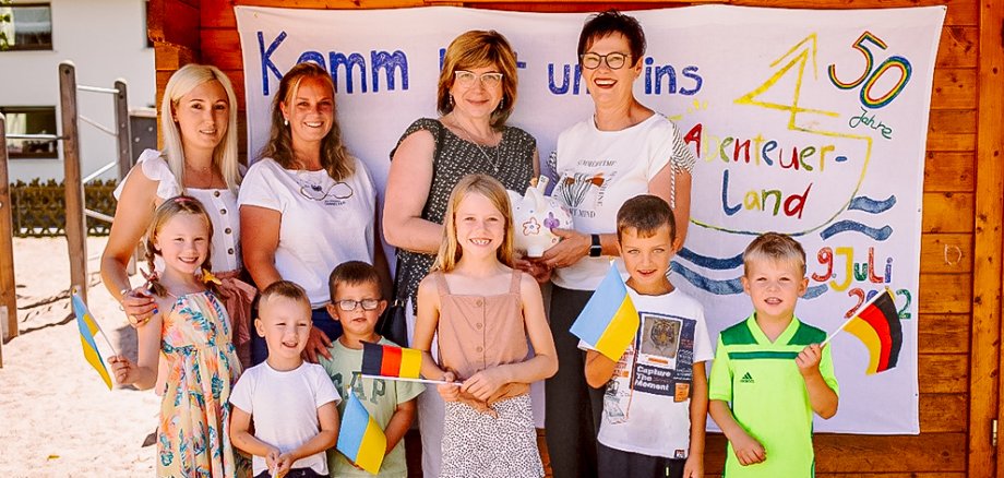 Viele Kinder und die Leiterin der Kita Abenteuerland überreichen die gesammelten Spenden.