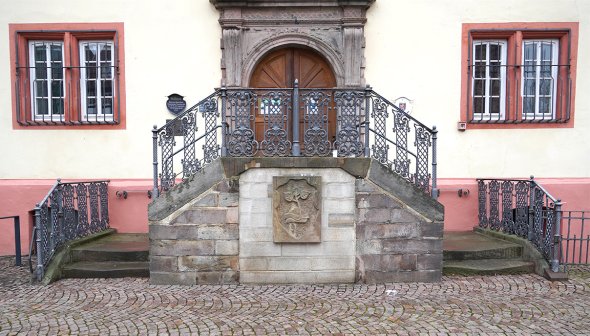 Ein gelbes Haus mit einer großen Treppe aus Stein davor. Die Treppe hat zwei Eingänge.