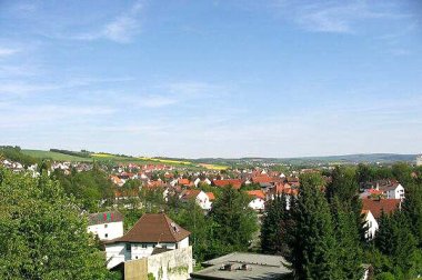 Häuser von Lispenhausen stehen im Vordergrund, Rapfsfelder, grüne Wiese und der blaue Himmel sind im Hintergrund zu finden.