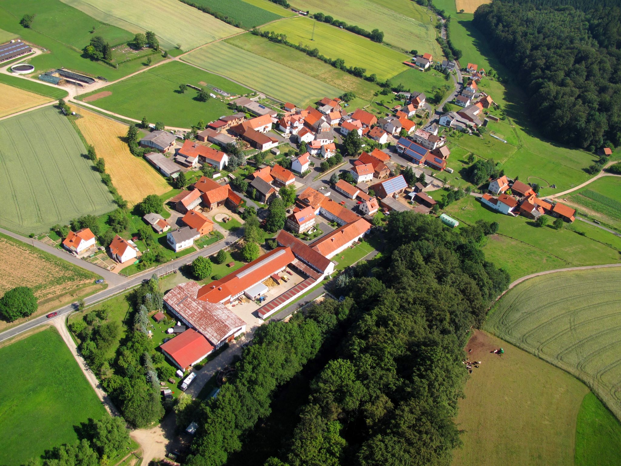 Luftaufnahme des Ortsteils Dankerode mit roten Häuserdächern inmitten einer saftigen grünen Landschaft.