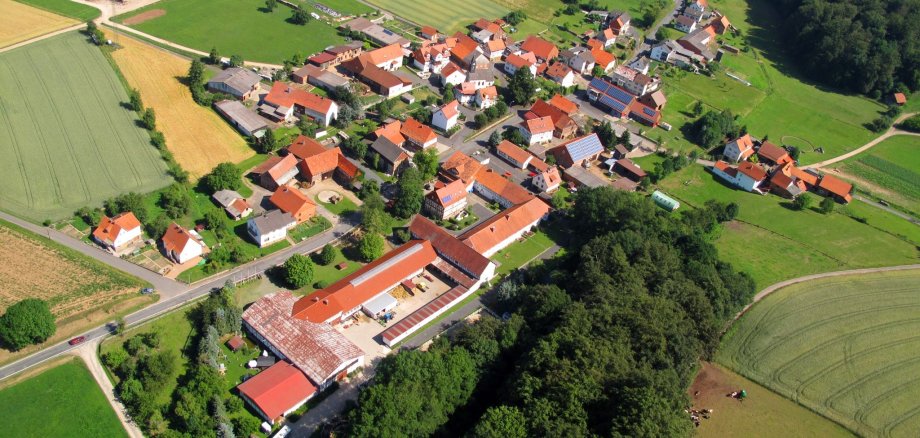 Luftaufnahme des Ortsteils Dankerode mit roten Häuserdächern inmitten einer saftigen grünen Landschaft.